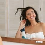 pretty girl blow drying hair in front of the mirror